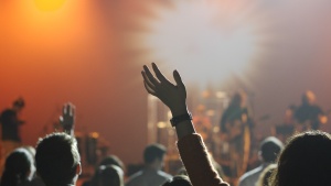 People with their arms up in the air worshiping while music is playing.