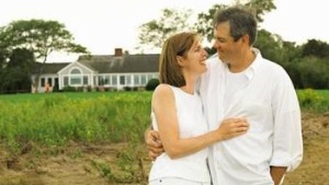 A married couple in front of a house.