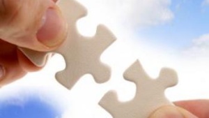 Hands Holding Jigsaw Puzzle Pieces In Front Of Blue Sky