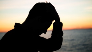 A silhouette of a man with his hand on his head.