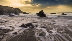 Sunset over the ocean - waves crashing into shore.