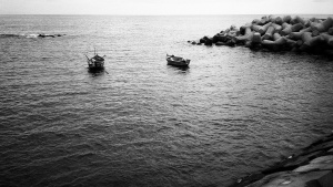 Small boats sitting in the bay of a sea.