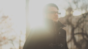 A young man walking with sun rays behind him.