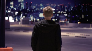 A person walking in a dark parking lot.