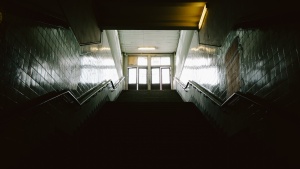 Dark stairs leading up to doors where light is coming through.