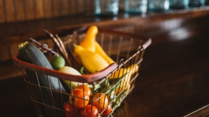 A wire shopping basket full of vegetables. 