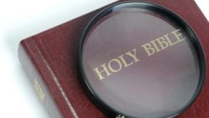 Magnifying glass over the words Holy Bible.