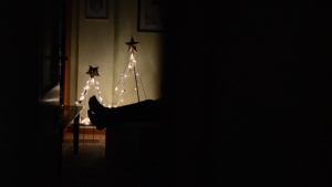 A person sitting in a dark room with Christmas lights.