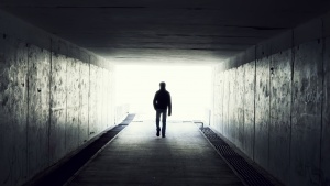 A man walking in a dark tunnel.