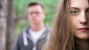 A young couple - woman in the foreground, man in the background blurred.