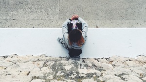 A woman sitting on a sidewalk.