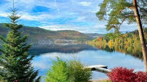 a bright blue lake and sky surrounded by green hills and trees