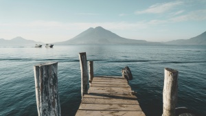 a dock leading out to a body of water with a mountain on the horizon