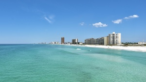 a clear ocean with the shoreline and city buildings in the background