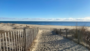 a sandy beach with wooden fenceposts on either side of a sandy path