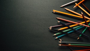 scattered colored pencils along the right edge of a dark background