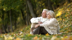 an older couple sitting outdoors amongst the leaves and trees