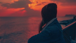 a woman turned to watch the sunset on the horizon