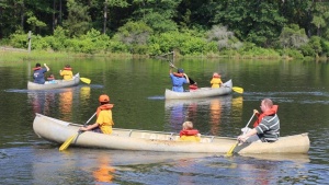 a group of children and UYC staff canoeing on a lake with trees in the background