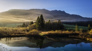 a mountainous landscape sitting in the background of a body of water