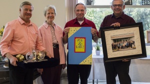 Peter Eddington, Media and Communications Services manager and Victor Kubik, president, award the Surratts with a card, keepsake bookends, and a photo of all home office employees that was also signed by employees.