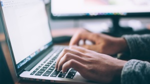 a pair of hands typing on a laptop