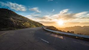 Man running on road towards sunrise.