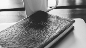 Bible and coffee mug on a table.