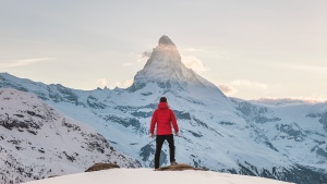 Photo of a man standing in front of a snowy mountain.