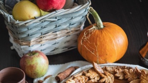 a basket of apples, pumpkin pie, coffee mug, and cinnamon stick