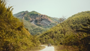 a hilly landscape with a road and a car