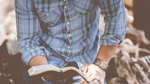 A man on his knees reading his Bible.