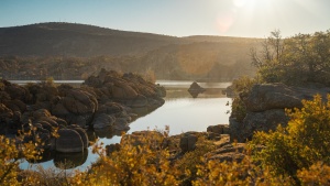 a landscape with a lake, rocks, and rolling hills