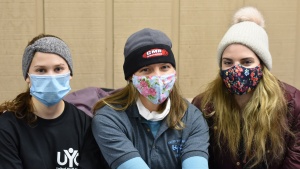 Three ladies on nursing staff at winter camp smile with masks on.