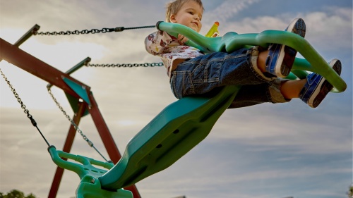 A little boy swinging on a swingset.