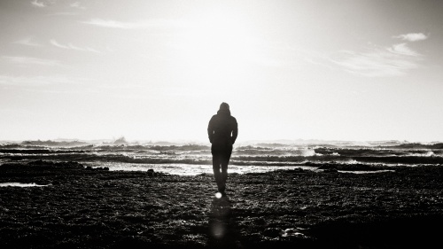 A main walking by the ocean shoreline.