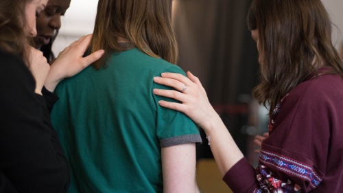 A group of women comforting praying for another lady.