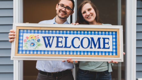 a man and a woman holding a sign that reads "welcome"