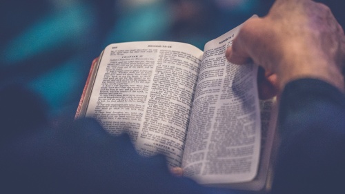 a hand turning the pages in an open Bible