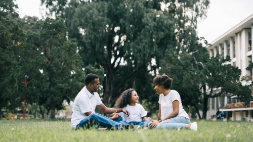 a family of three sitting outdoors in the grass