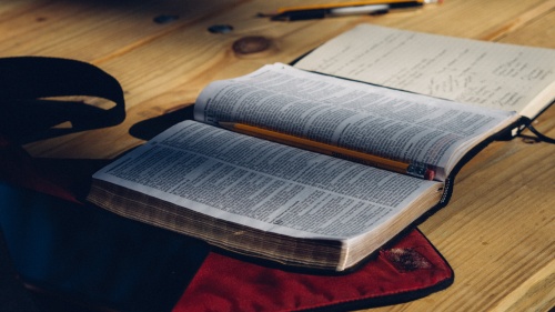 A Bible and notebook laying on a table.