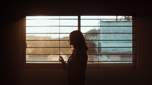 a woman standing in a dark room with a window in the background