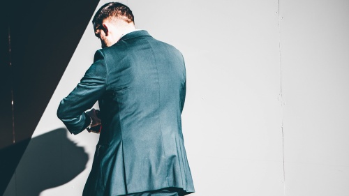 A man walking looking at his wrist.