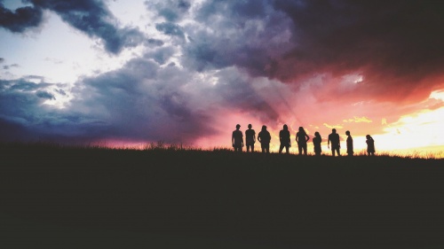 Silhouette of nine persons standing on the hill.
