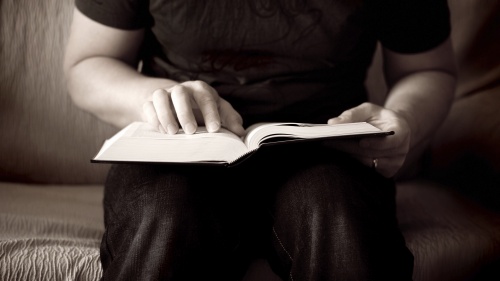 A Bible on the lap of a man.