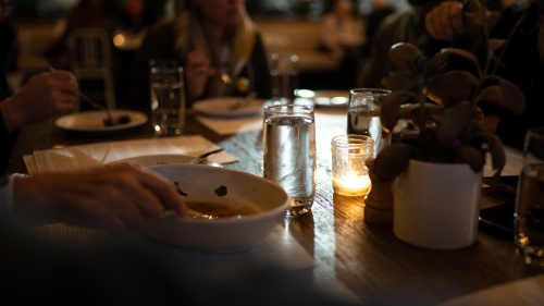 a group of people gathered around a dinner table, lit by candlelight