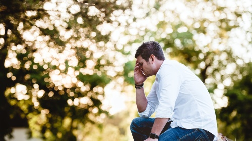 a man sits outside with his head in his hand