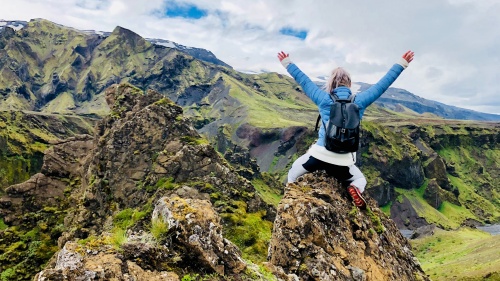 Woman sitting on rocky mountain during daytime.