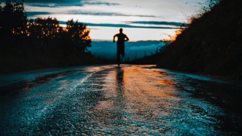 Silhouette photo of a person running on road.