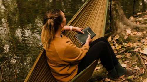 A woman sitting in a hammock holding a Bible.